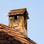 A,Brick,Chimney,Crowned,With,A,Tiled,Cap,Shows,Heavy