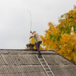 Male,Chimney,Sweep,Cleans,The,Chimney,On,The,Roof,Of