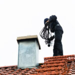 Chimney,Sweep,Standing,On,Roof,Of,Home,Working