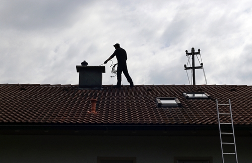 A,Chimney,Sweep,Cleans,The,Chimney,On,A,House,Roof